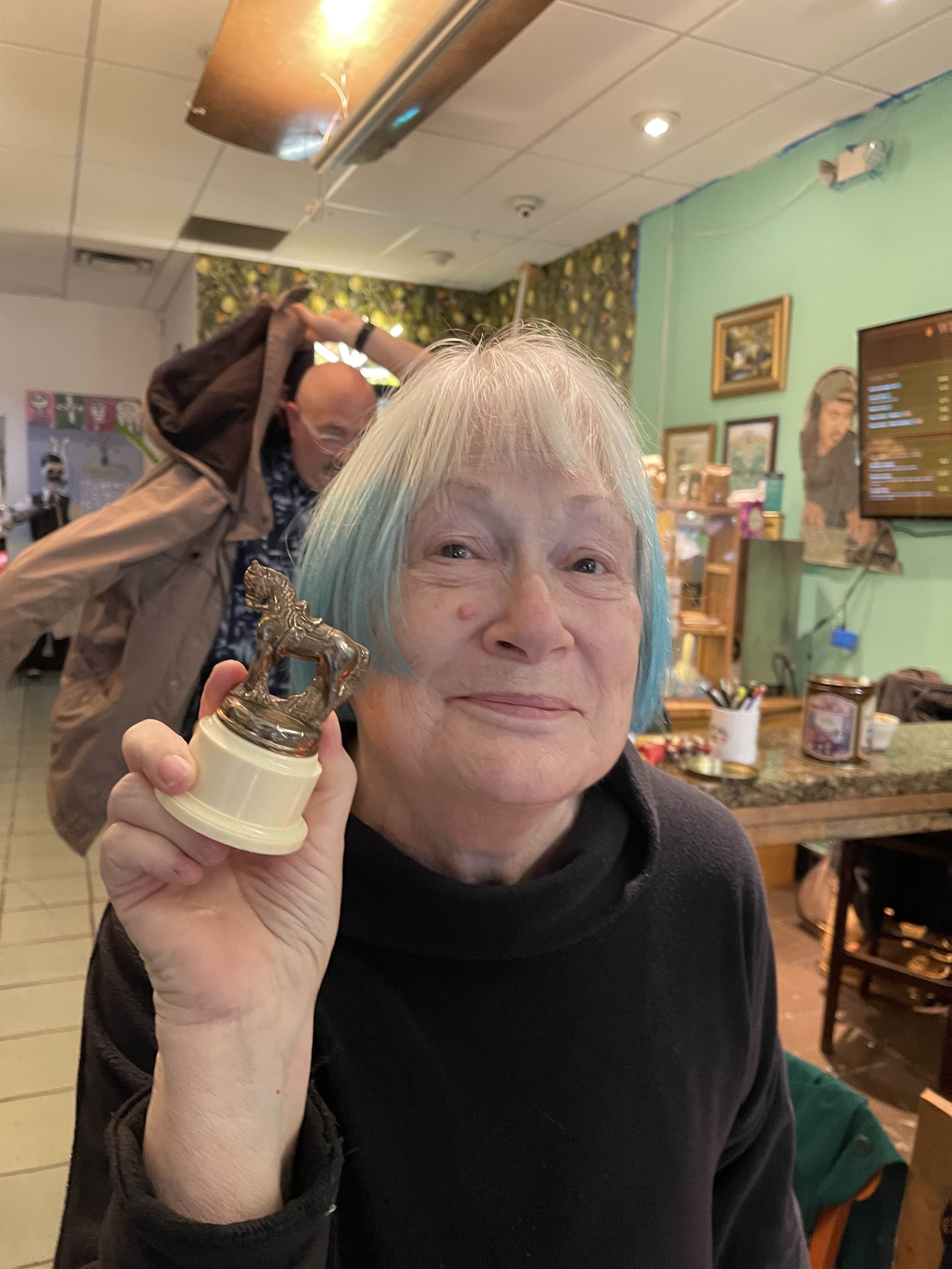 A smiling participant holding a small trophy at a Democracy Haiku gathering